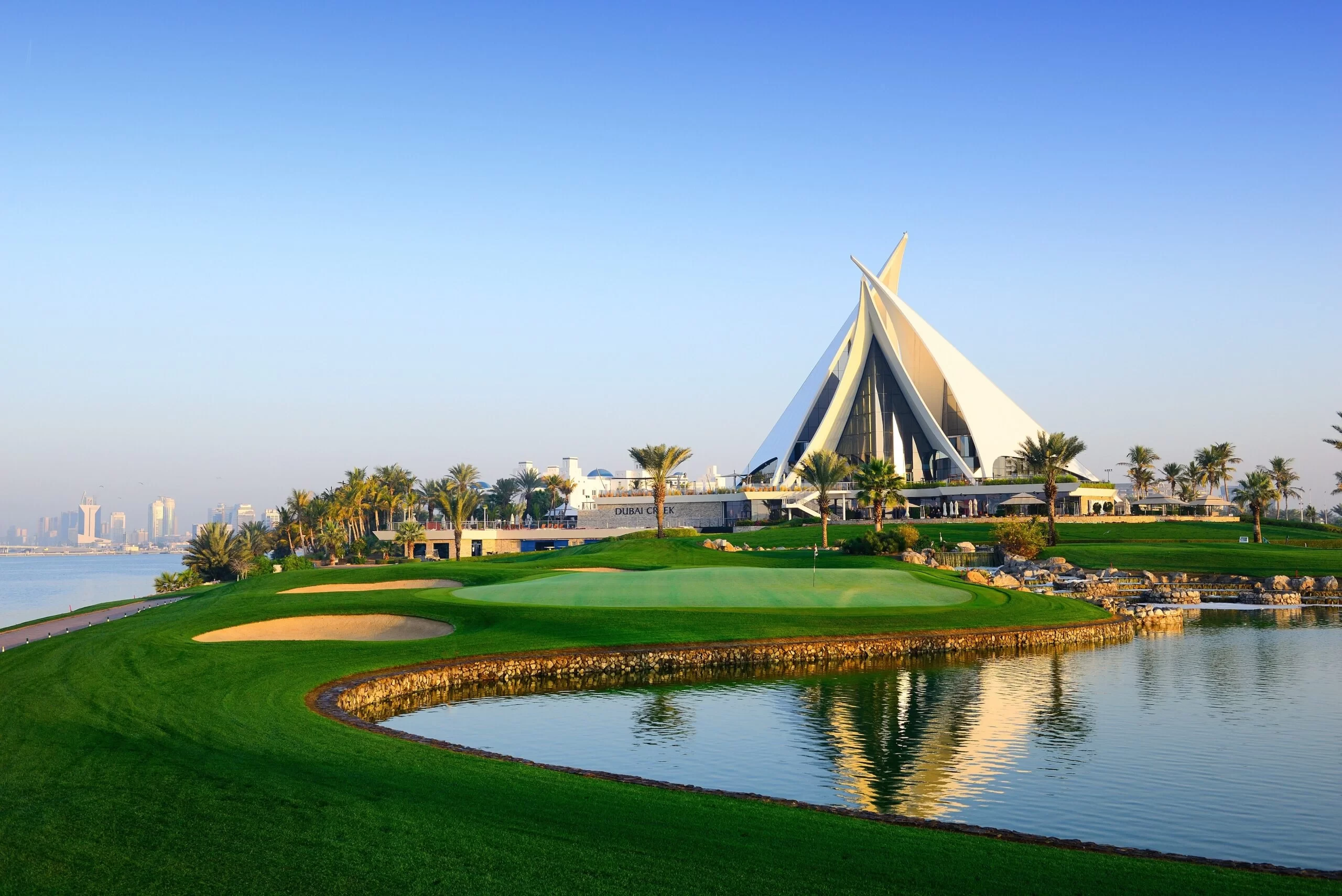 Dubai Creek Golf & Yacht Club, lush greens, reflecting water, clear sky.