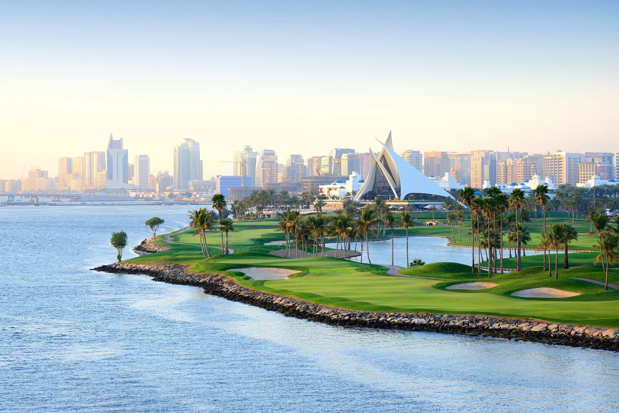Dubai Creek Golf & Yacht Club by waterfront, city skyline view.