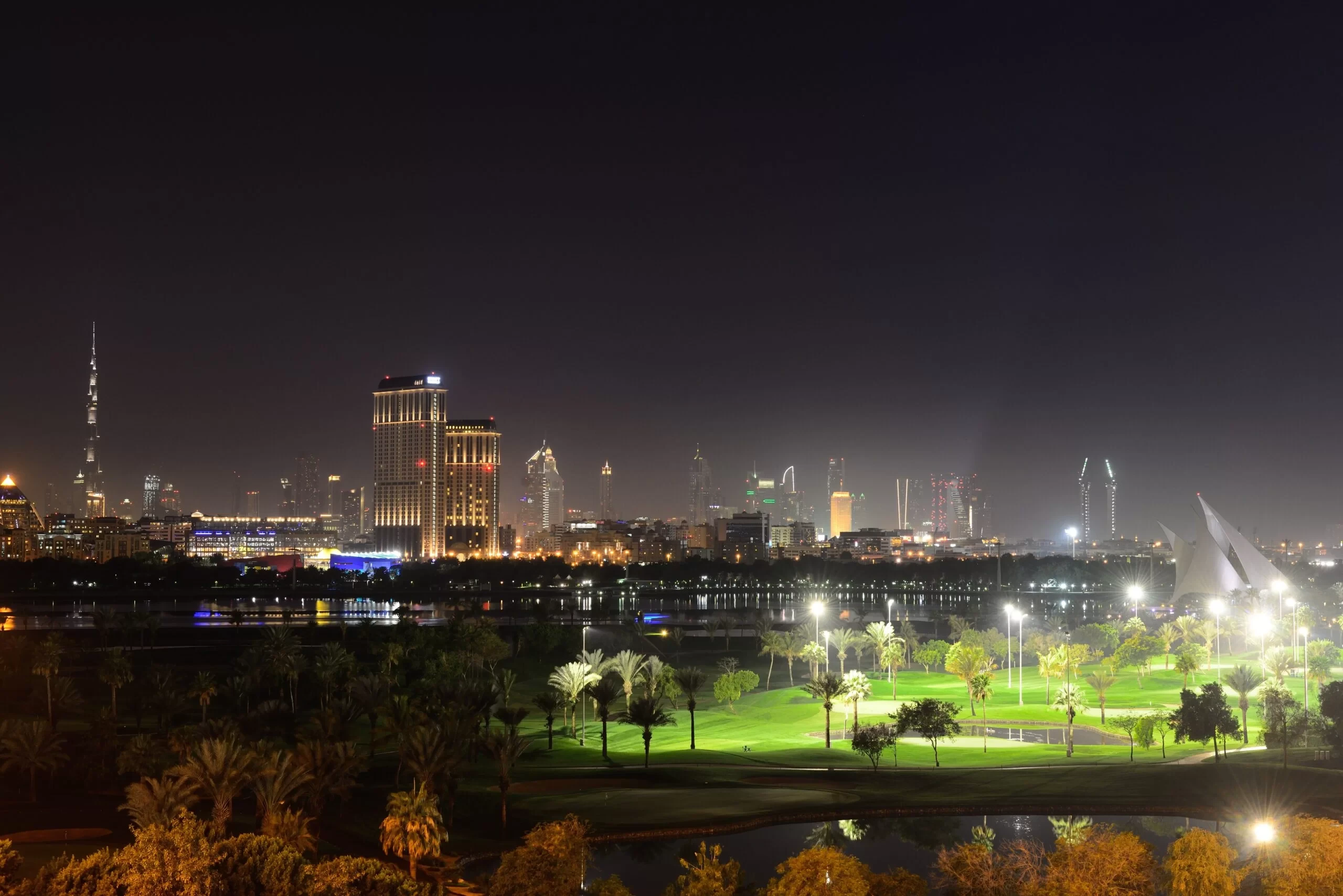 Dubai Creek Golf & Yacht Club at night with city skyline.