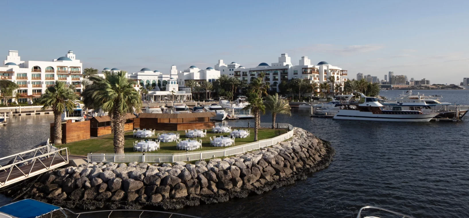 Dubai Creek Golf & Yacht Club waterfront with yachts and palm trees.