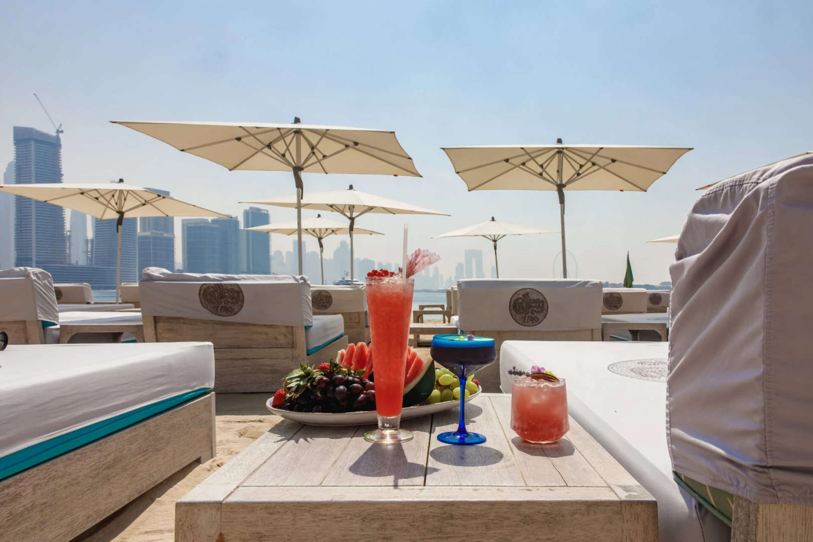 Gallery 7/40 Dubai beachside lounge with drinks and city skyline.