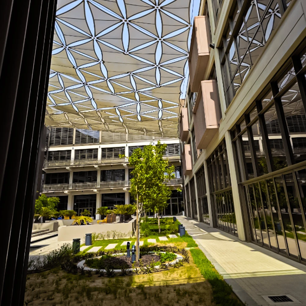 Geometric canopy above University of Birmingham Dubai courtyard with plants.