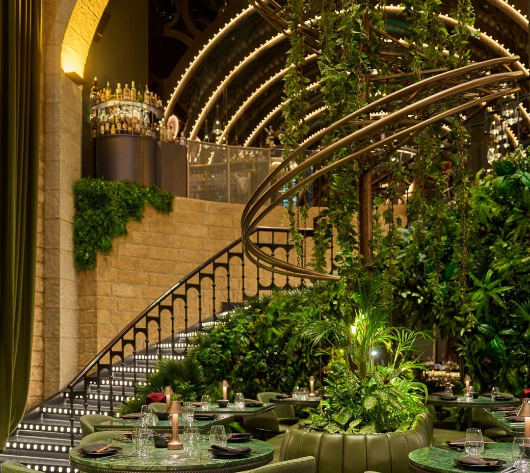 Lush interior of Amelia Restaurant & Lounge, Dubai with greenery and lights.