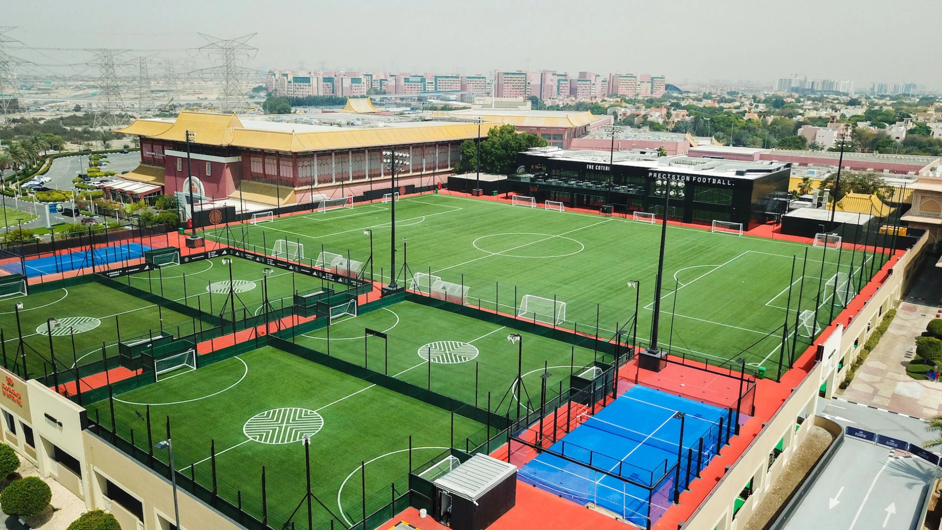 Precision Football sports complex with multiple fields, Dubai skyline visible.
