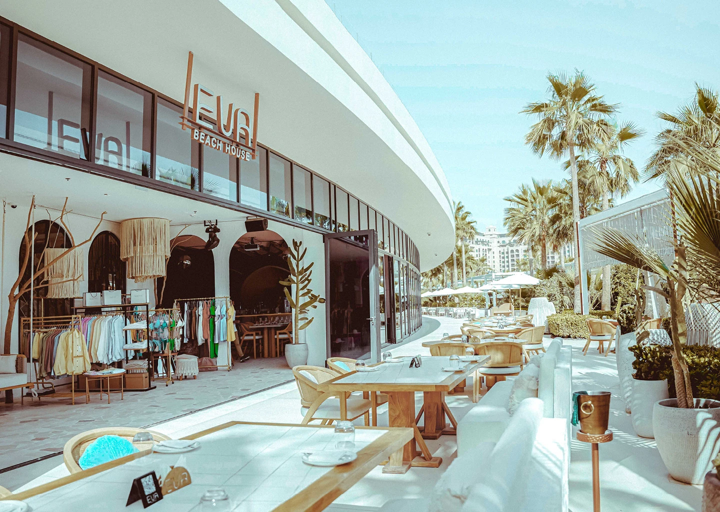 EVA Beach Restaurant outdoor seating with palm trees, Dubai.