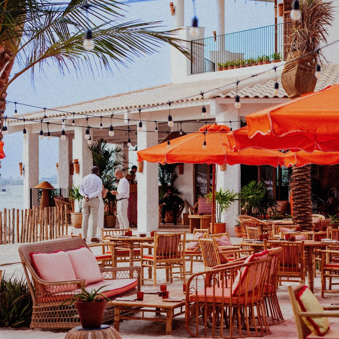 Outdoor seating with orange umbrellas at Tagomago Dubai beach venue.