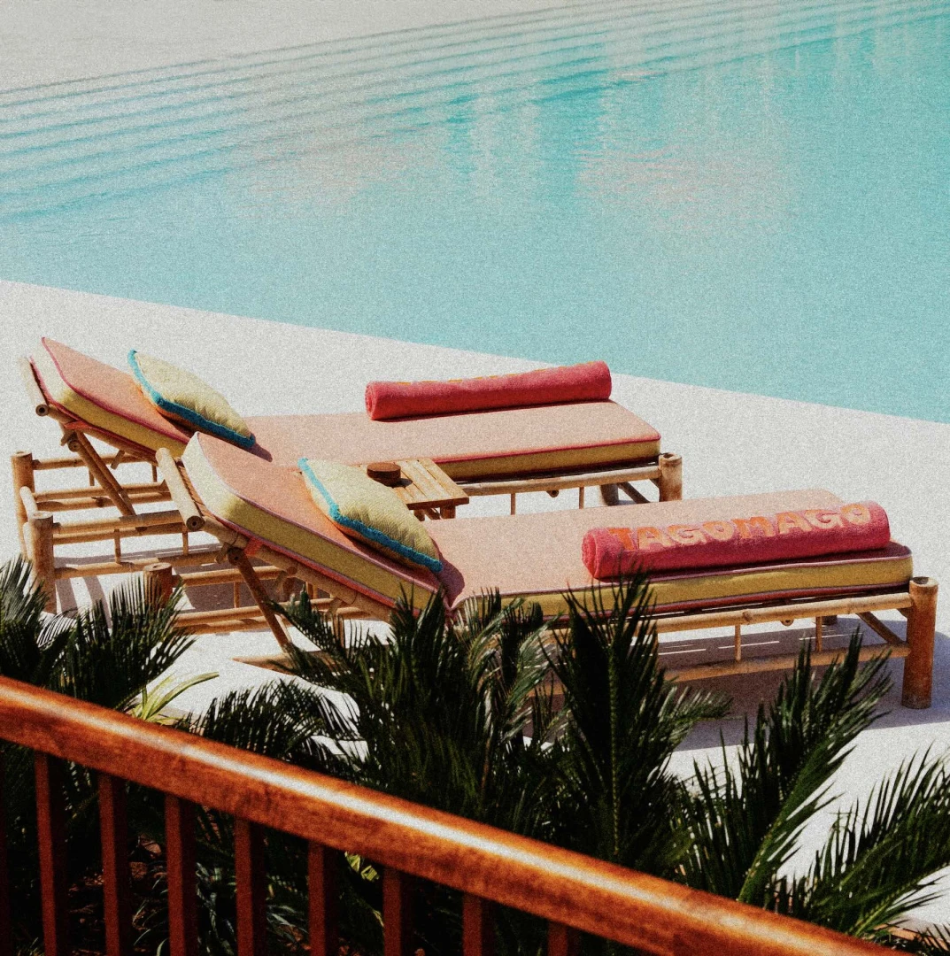 Poolside loungers at Tagomago Dubai with vibrant cushions and towels.