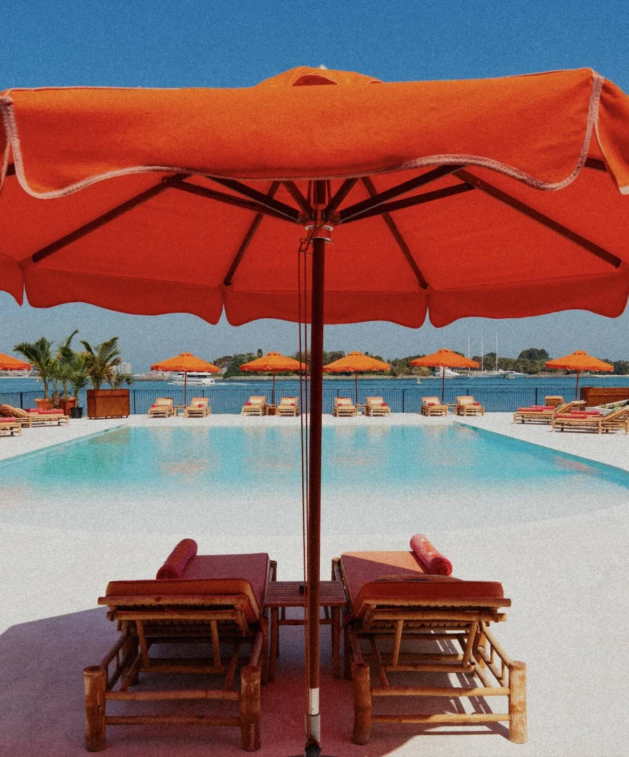 Tagomago Dubai poolside with orange umbrellas and loungers.