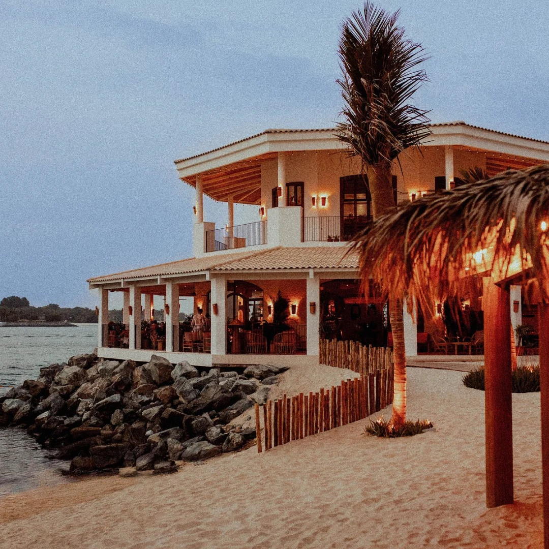 Tagomago Dubai beachfront venue with palm trees and evening lights.