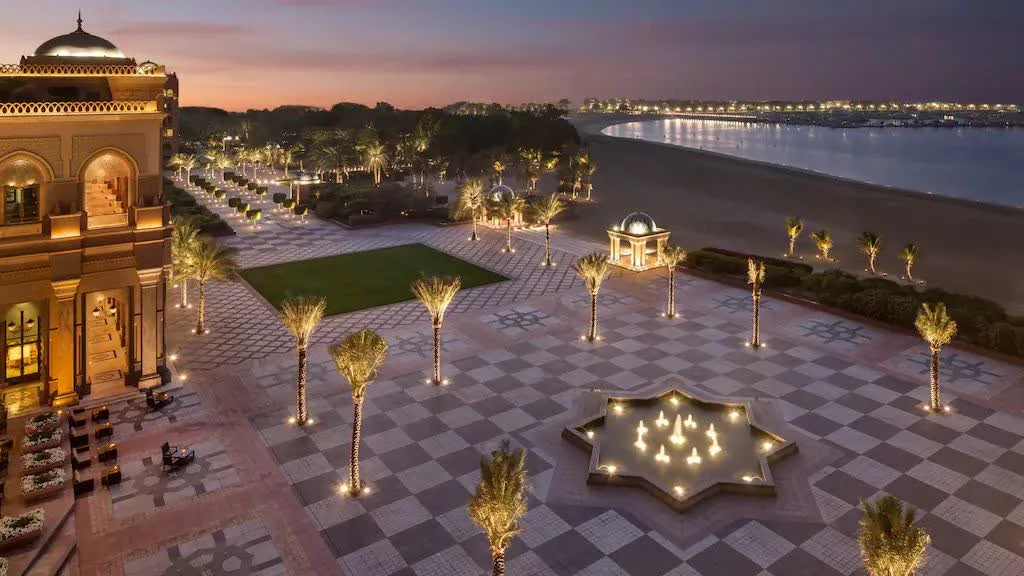 Emirates Palace courtyard at dusk, Abu Dhabi, with illuminated fountain.