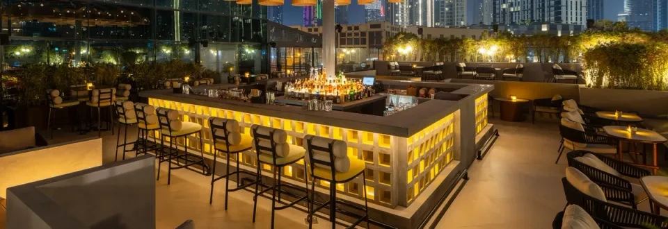 Elegant rooftop bar at Treehouse, Taj Dubai, with city skyline view.