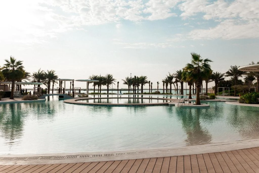 Erth Hotel Abu Dhabi pool with palm trees and ocean view.