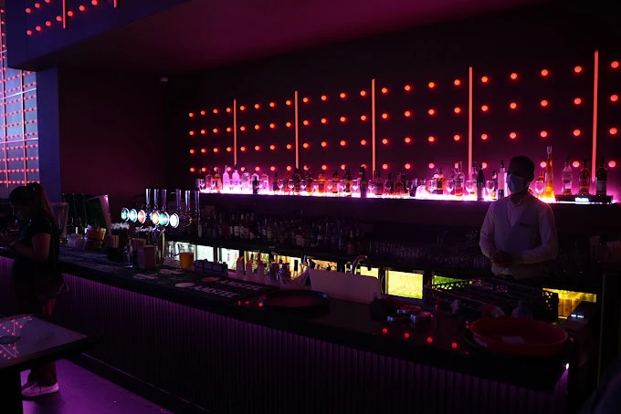 Dimly lit bar at Boracay Night Club, Dubai with neon lights.