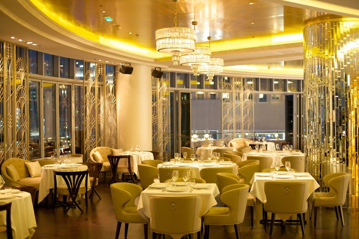 Elegant dining area at Atelier M, Dubai with chandeliers and city view.