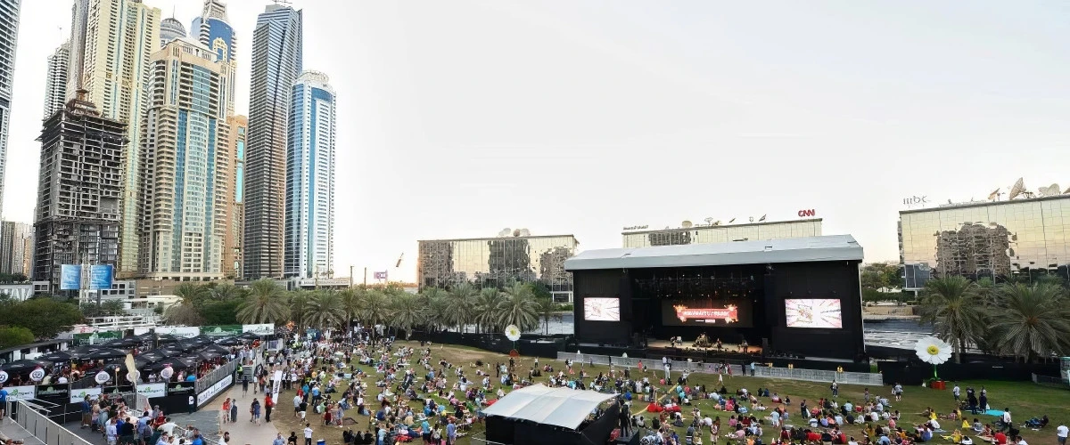 Crowd gathered at Dubai Media City Amphitheatre with skyscrapers in background.