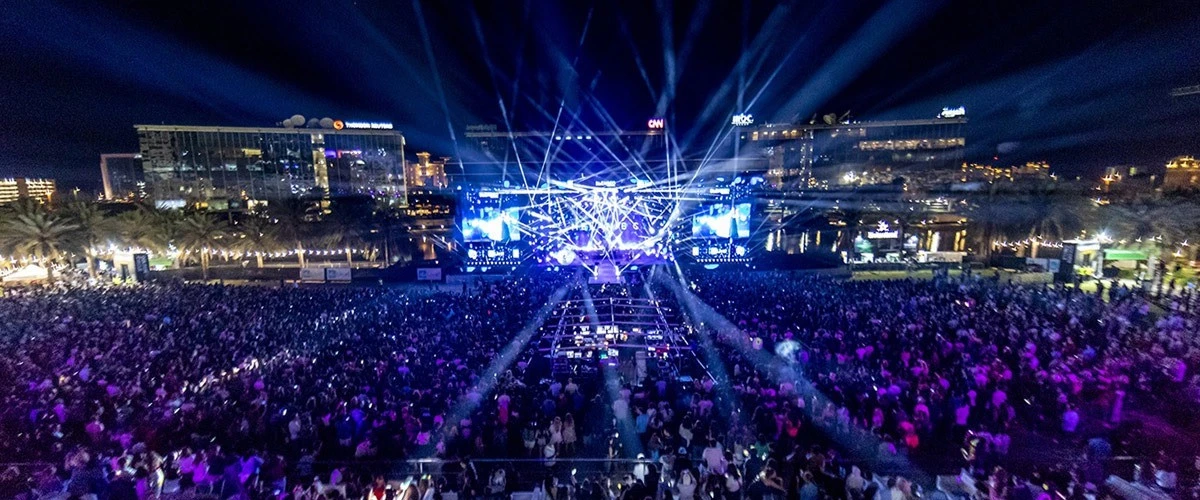 Crowded night concert at Dubai Media City Amphitheatre, vibrant lights.
