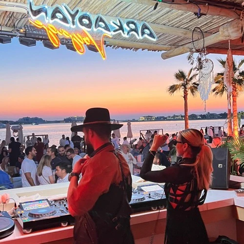 DJ performing at sunset in Surf Club Dubai, lively crowd.