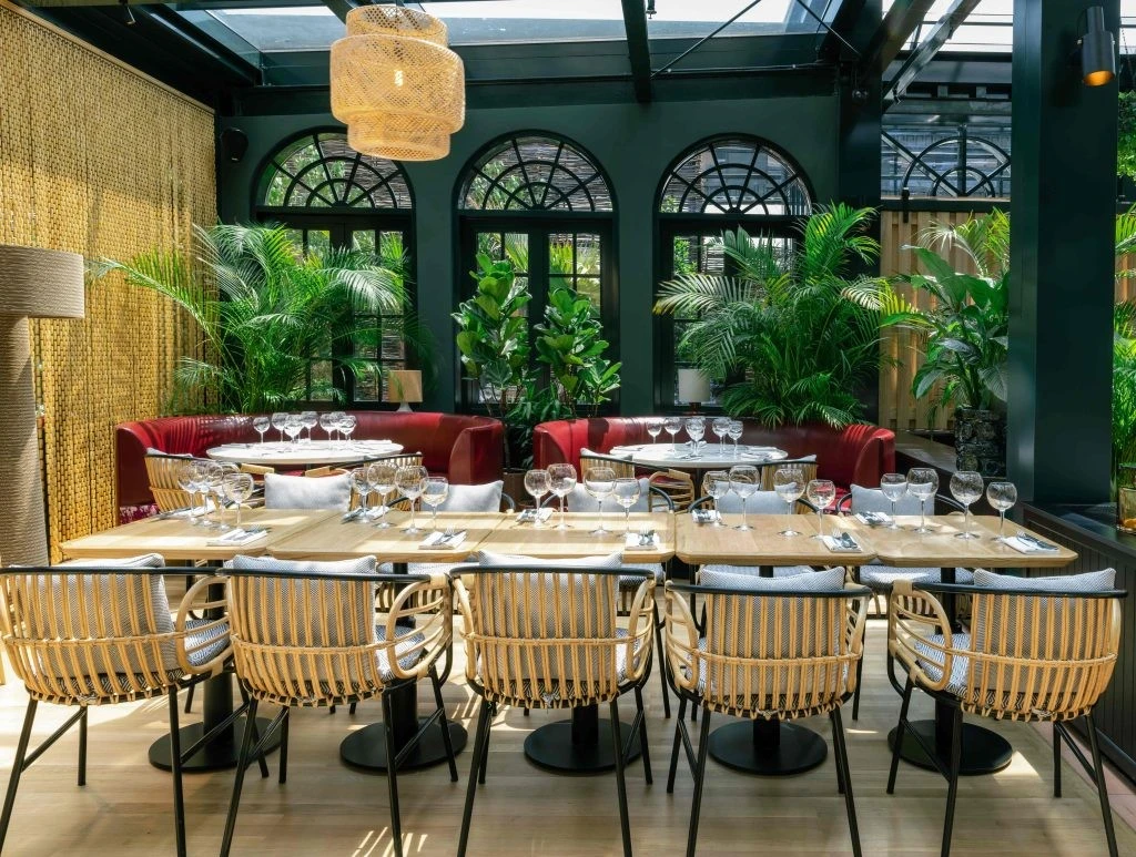 Elegant dining area at Eugène Eugène Restaurant, Dubai with lush greenery.