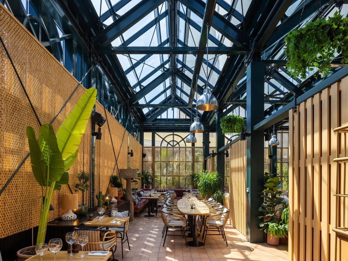 Eugène Eugène Restaurant Dubai, elegant dining area with plants and skylights.