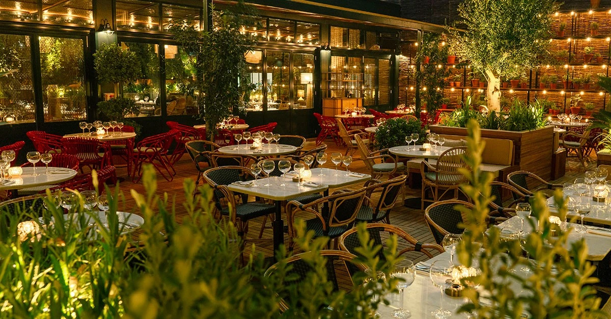 Outdoor dining at Eugène Eugène Dubai, illuminated with warm lighting.