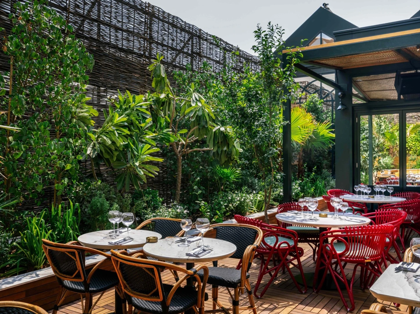 Eugène Eugène Restaurant Dubai outdoor seating with lush greenery.