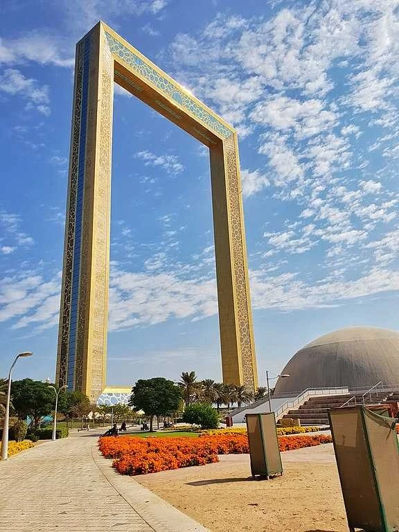 Dubai Frame towering over Zabeel Park under blue sky.