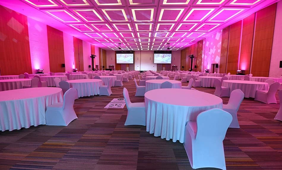 ADNEC Centre Abu Dhabi conference hall with pink lighting and round tables.