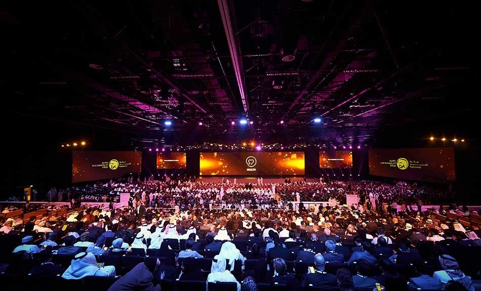 Crowded conference at ADNEC Centre, Abu Dhabi with vibrant lighting.