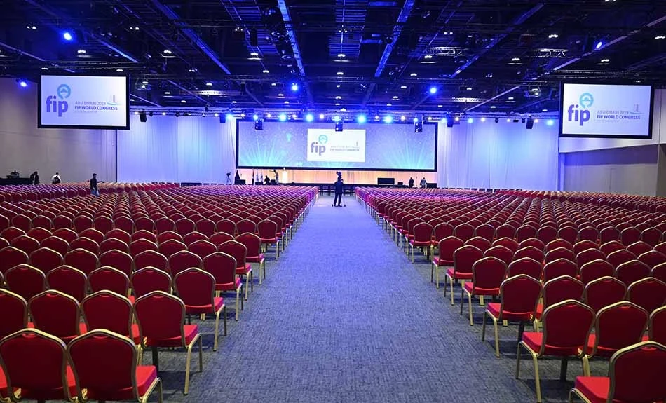 ADNEC Centre Abu Dhabi conference hall with rows of red chairs.