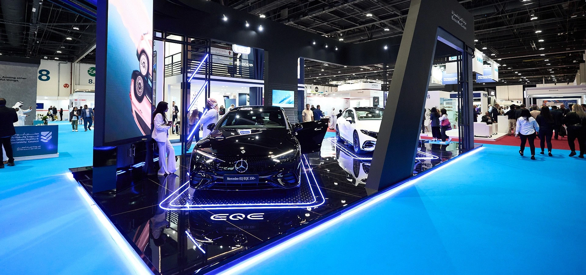 ADNEC Centre Abu Dhabi exhibition with cars and attendees.