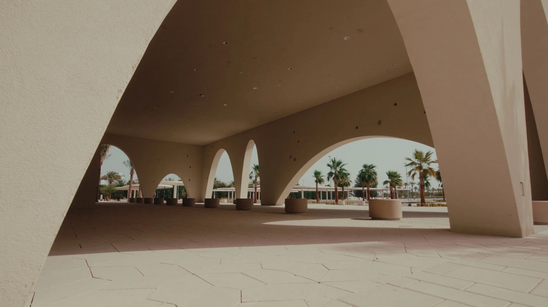 Arched walkway at Erth Hotel Abu Dhabi with palm trees.