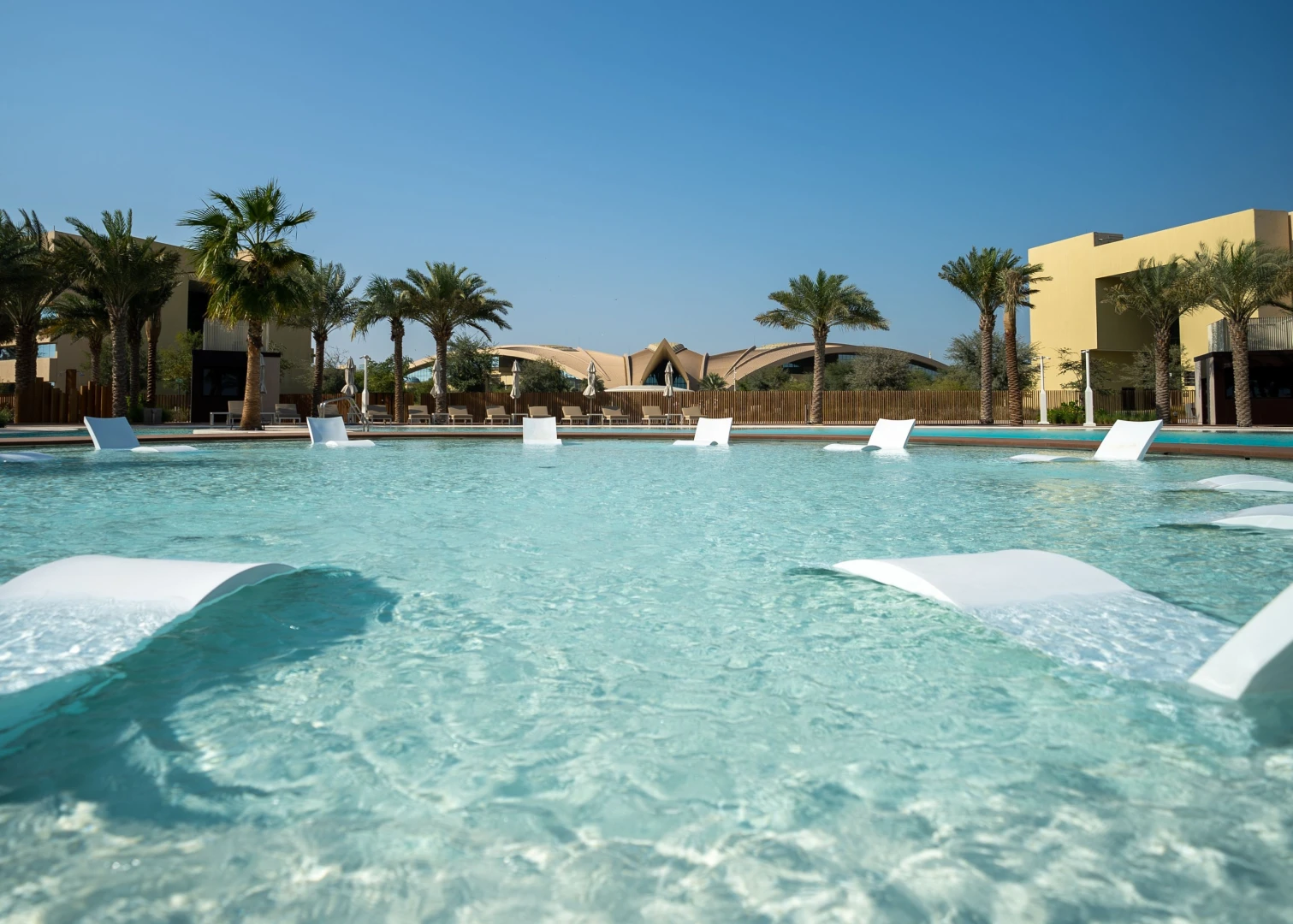 Poolside view at Erth Hotel Abu Dhabi with palm trees.