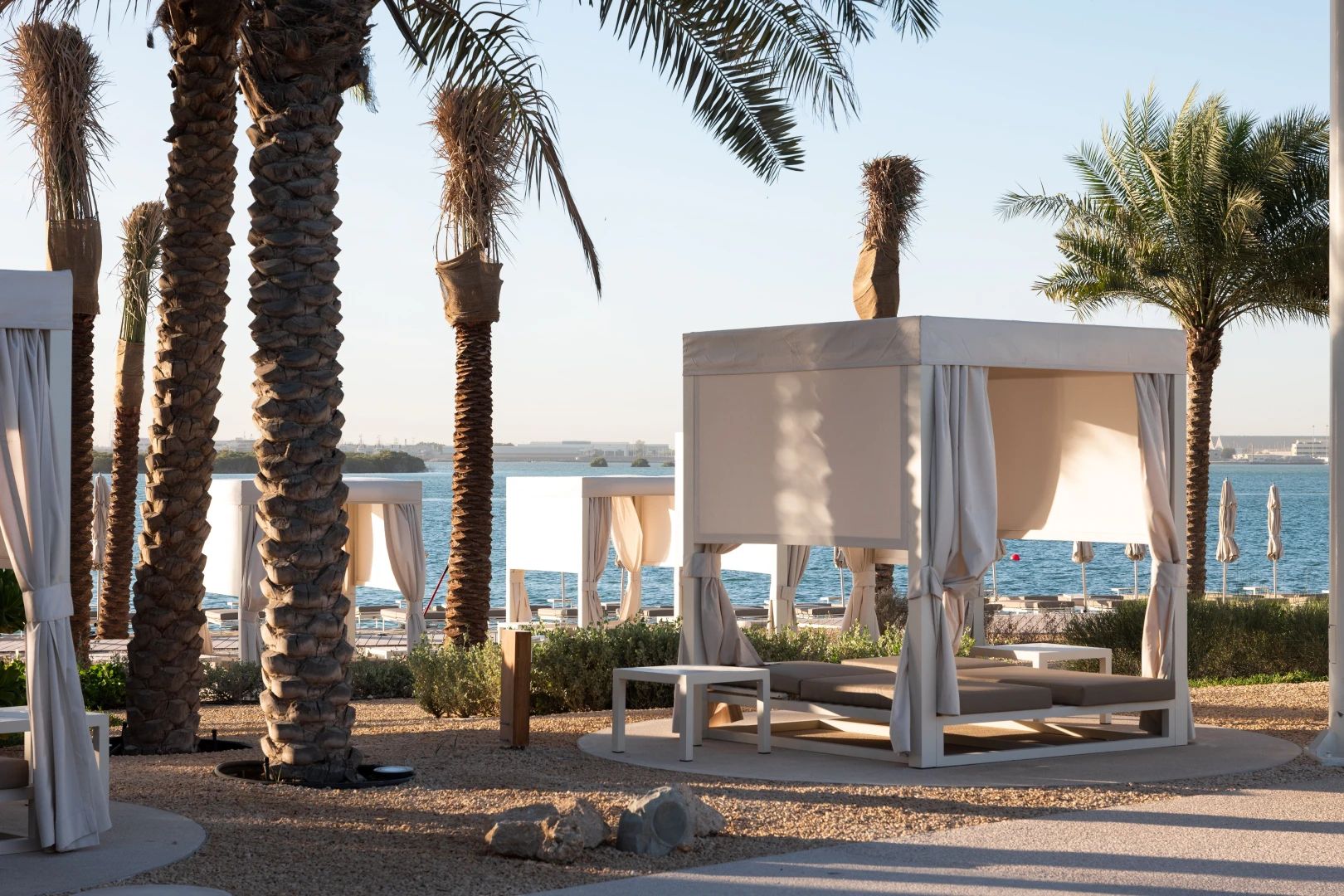 Palm trees and cabanas by the sea at Erth Hotel Abu Dhabi.