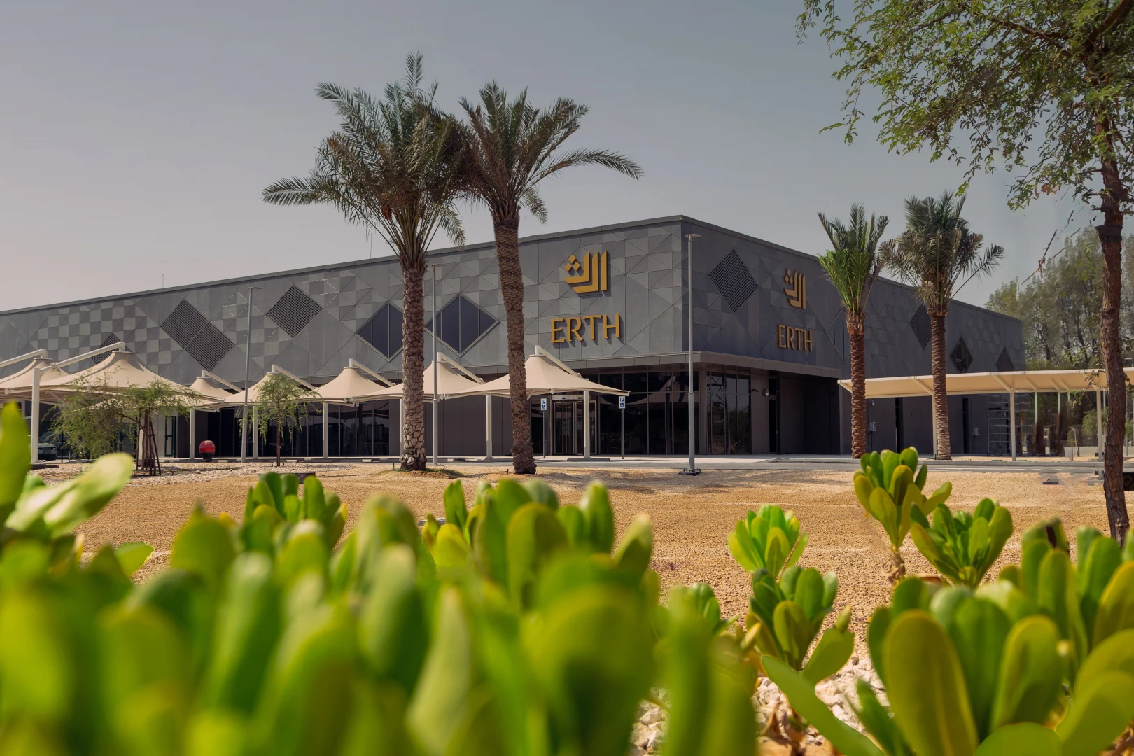 Erth Hotel Abu Dhabi exterior with palm trees and greenery.