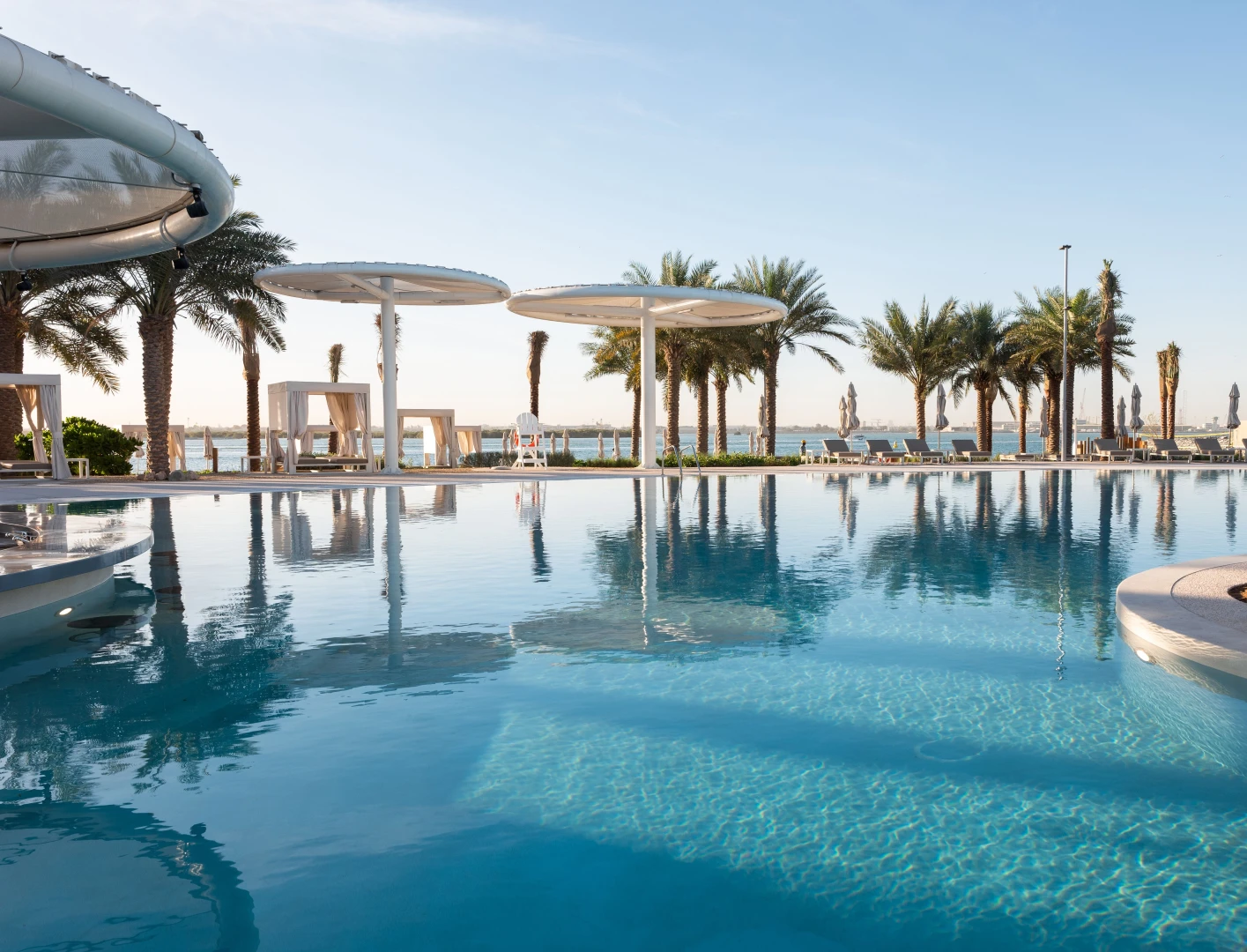 Luxurious poolside at Erth Hotel Abu Dhabi with palm trees.