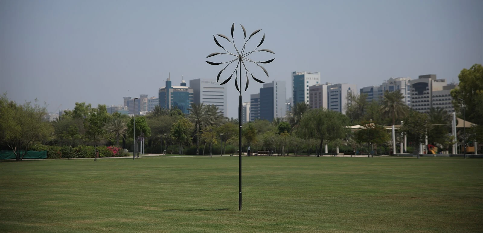 Umm Al Emarat Park lawn with Abu Dhabi skyline backdrop.