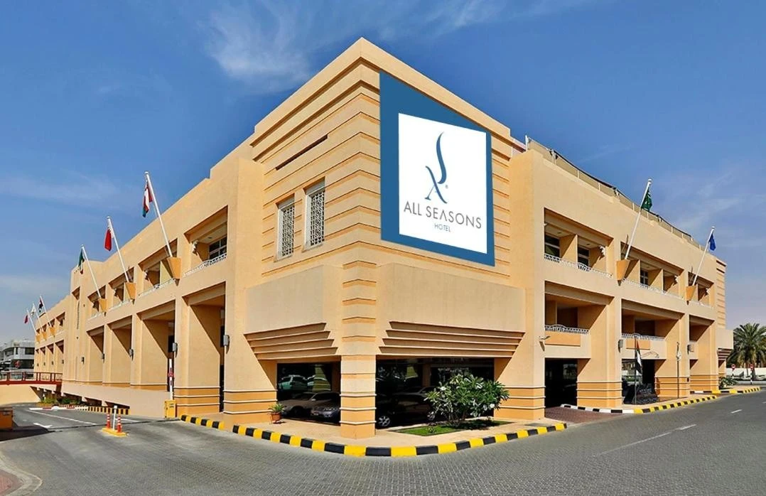 All Seasons Hotel Al Ain exterior with flags and signage.