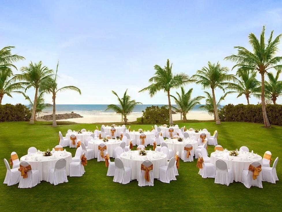 Outdoor banquet setup on lawn, Kempinski Hotel Ajman, near beach.