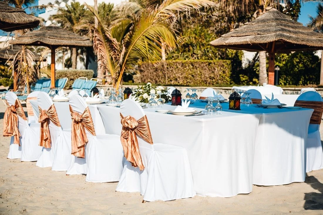 Beachfront dining setup at Kempinski Hotel Ajman with decorated chairs.