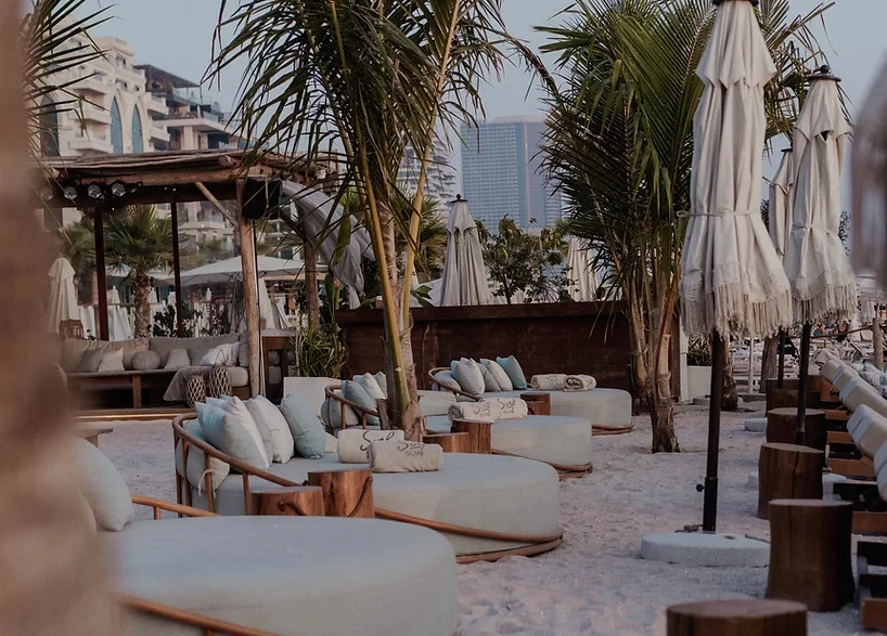 Beachside lounge area at Surf Club Dubai with palm trees.