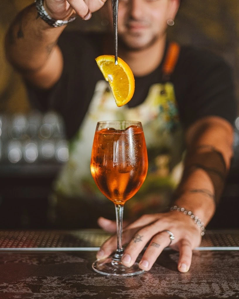 Bartender garnishing cocktail with orange slice at Monkey Bar Dubai.
