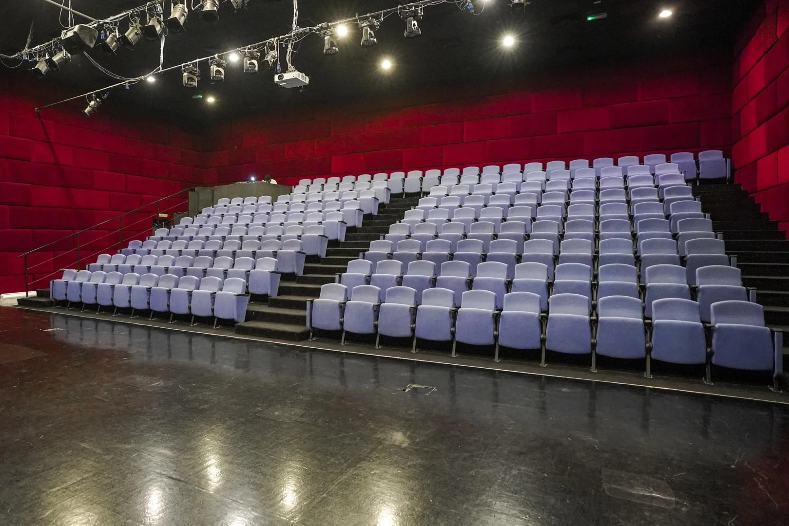 Empty theater seating at The Junction Dubai, red walls, overhead lights.