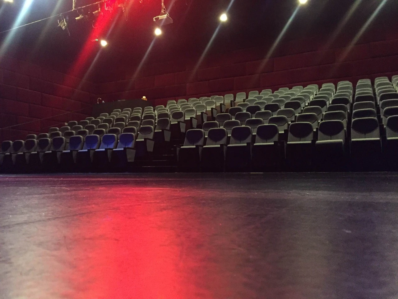 Empty theater seating at The Junction Dubai with red lighting.