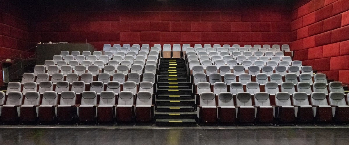 Empty theater seating at The Junction Dubai, red walls, central aisle.