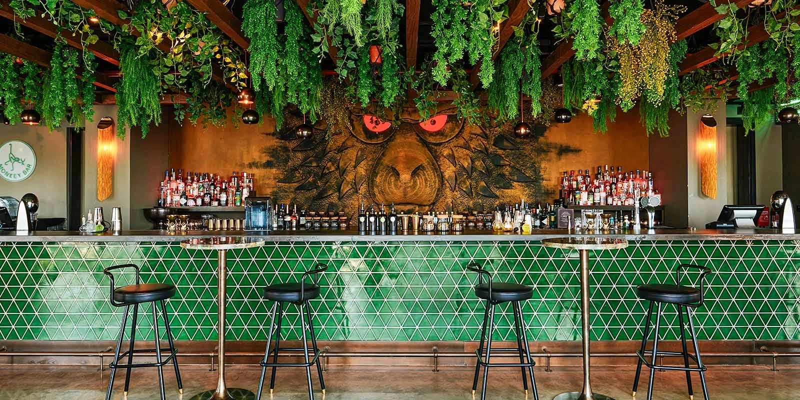 Monkey Bar Dubai interior with green tiles and hanging plants.