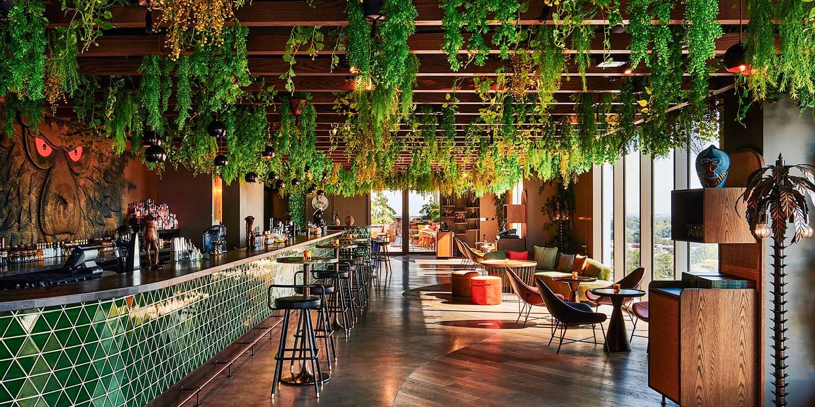 Lush interior of Monkey Bar Dubai with hanging plants and bar seating.