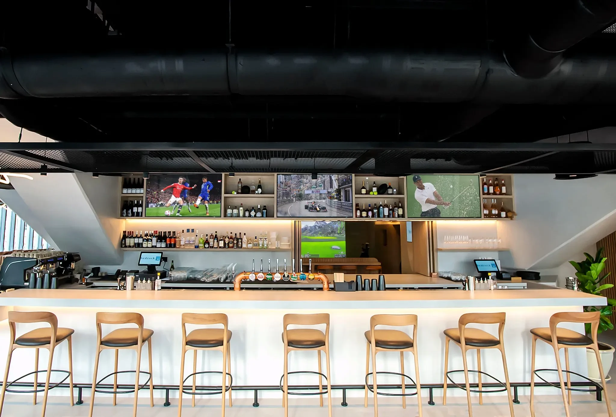 Modern bar at Bedrock Pier 7, Dubai with sports screens.