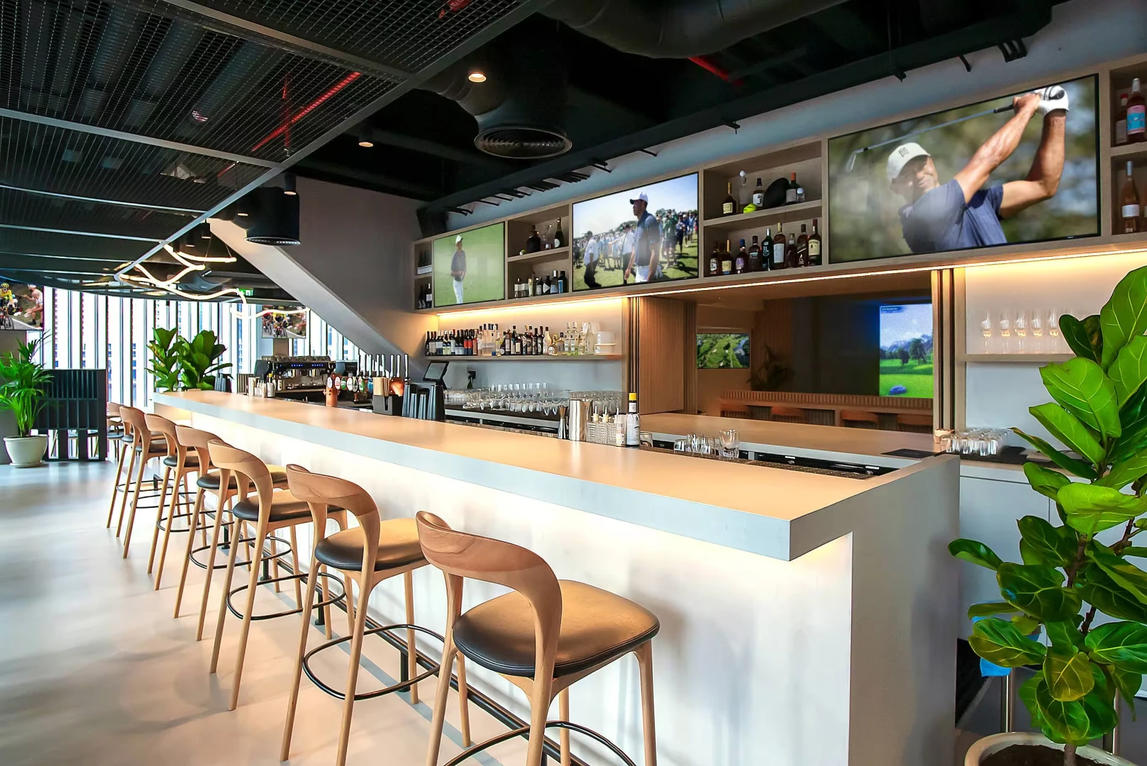 Modern bar interior at Bedrock Pier 7, Dubai, with seating and screens.