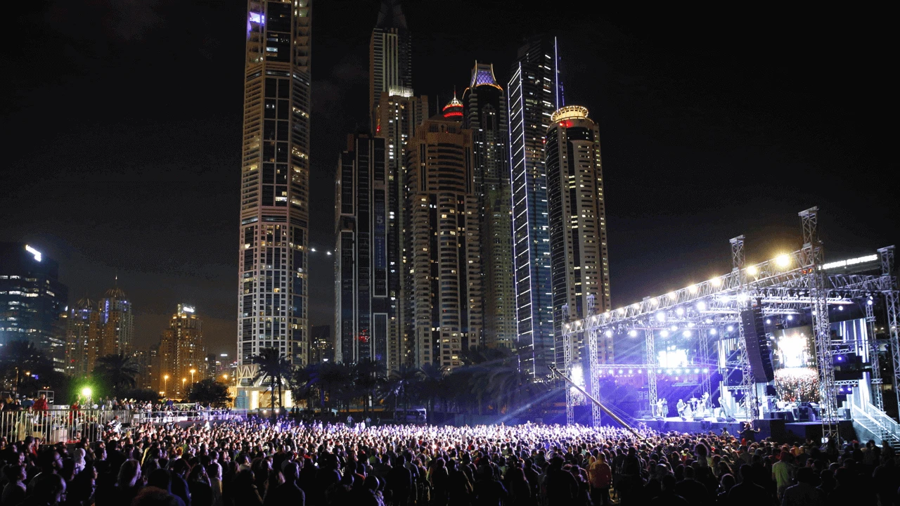 Crowd at Dubai Media City Amphitheatre concert, skyscrapers in background.