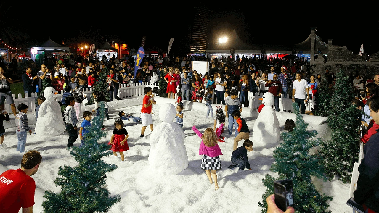 Children playing in artificial snow at Dubai Media City Amphitheatre.